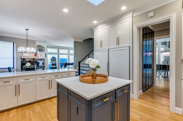 kitchen with pendant lighting, light hardwood / wood-style flooring, white cabinetry, and a kitchen island