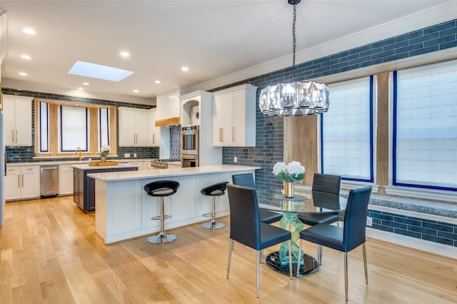 kitchen featuring light wood-type flooring, white cabinetry, hanging light fixtures, and a kitchen island