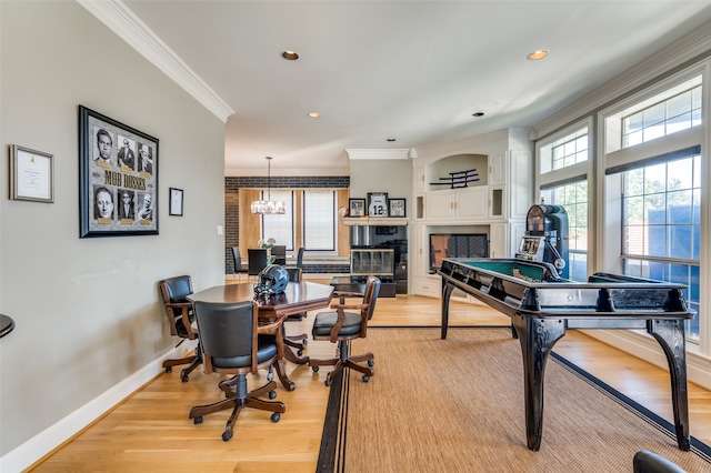 recreation room with light wood-type flooring, an inviting chandelier, and crown molding