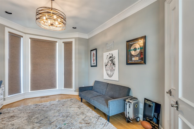 living area with ornamental molding, a notable chandelier, and hardwood / wood-style flooring