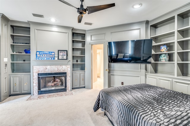 bedroom featuring light carpet, ceiling fan, crown molding, and a premium fireplace