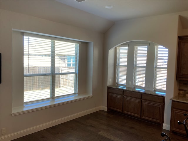 unfurnished dining area featuring dark wood-type flooring and vaulted ceiling