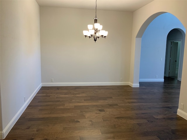 empty room featuring a chandelier and dark hardwood / wood-style floors