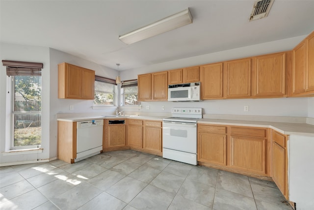 kitchen featuring sink, white appliances, hanging light fixtures, and light tile patterned floors