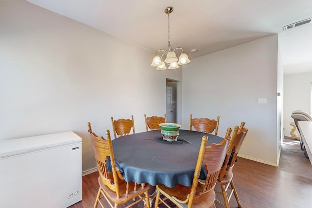 dining area featuring dark wood-type flooring and a chandelier