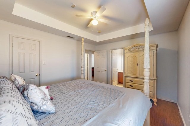 bedroom with a tray ceiling, ceiling fan, and hardwood / wood-style flooring