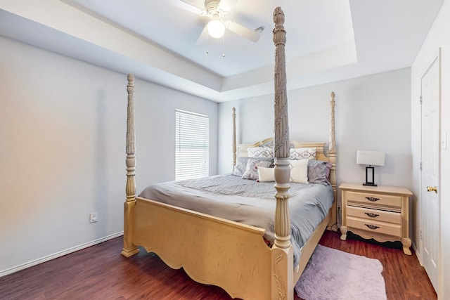 bedroom with dark hardwood / wood-style flooring, a raised ceiling, and ceiling fan