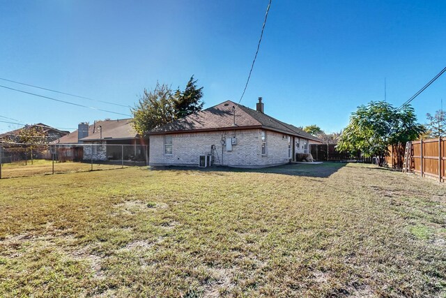 rear view of property with a yard and central AC