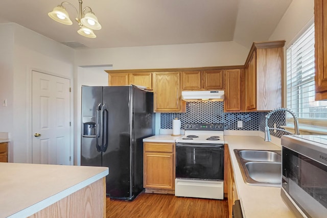 kitchen with tasteful backsplash, black fridge, white electric range oven, light hardwood / wood-style flooring, and hanging light fixtures