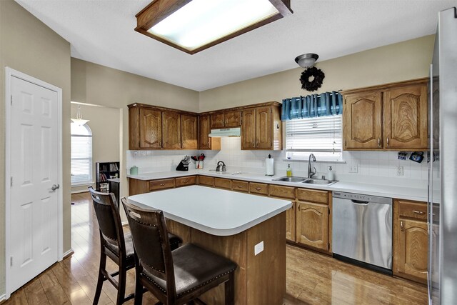 kitchen with tasteful backsplash, sink, light hardwood / wood-style floors, and appliances with stainless steel finishes