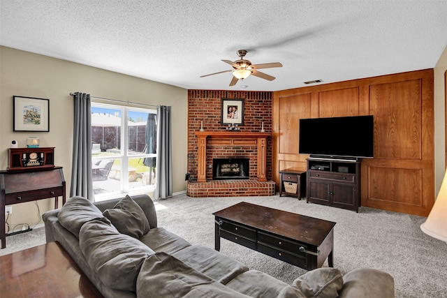 living room featuring a textured ceiling, light colored carpet, a brick fireplace, and ceiling fan