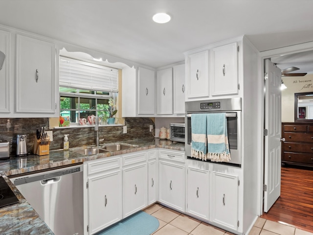 kitchen featuring appliances with stainless steel finishes, light tile patterned floors, white cabinetry, and sink