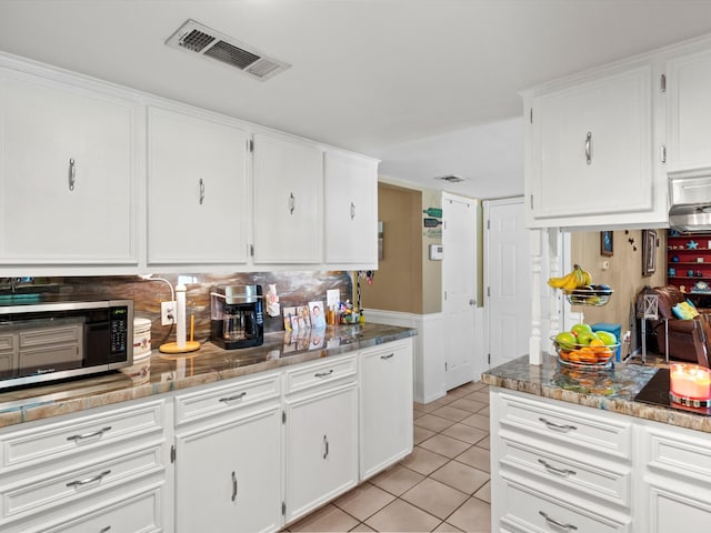 kitchen featuring dark stone countertops, black stovetop, white cabinets, and light tile patterned flooring