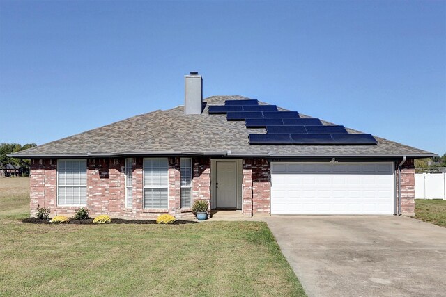 view of front of house featuring a front lawn, a garage, and solar panels