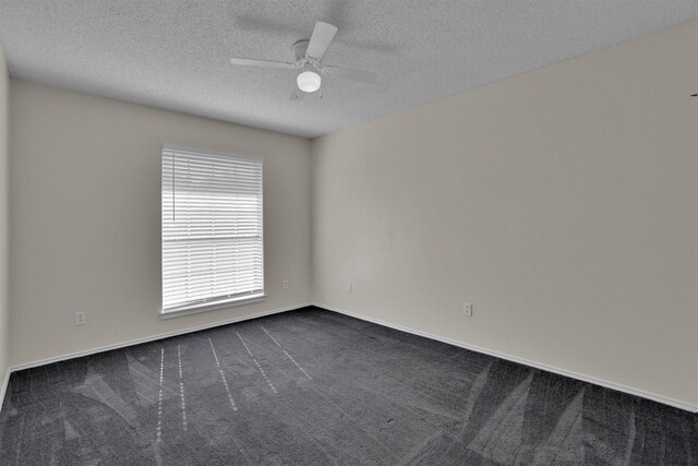 spare room featuring dark colored carpet, a textured ceiling, and ceiling fan