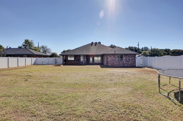 back of property with a lawn and a trampoline