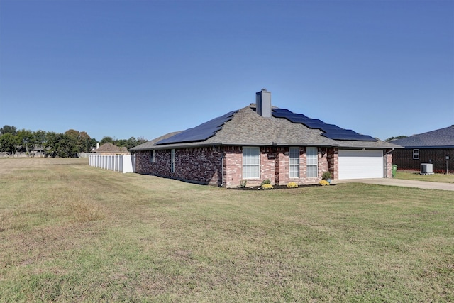 view of front facade featuring a front yard, solar panels, a garage, and central AC unit