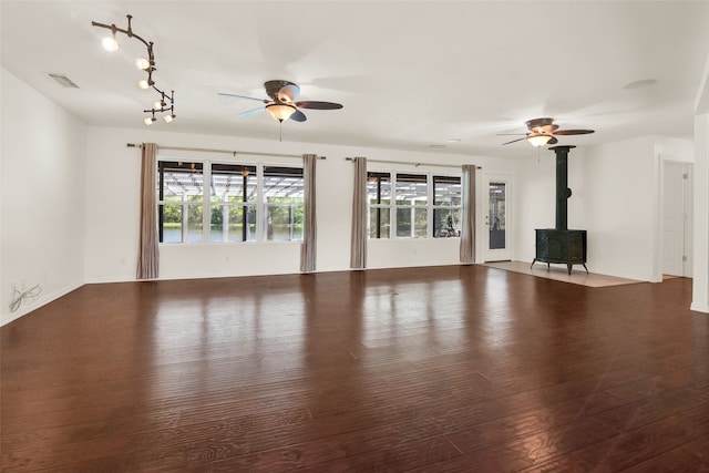 unfurnished living room featuring hardwood / wood-style flooring, a wood stove, and ceiling fan