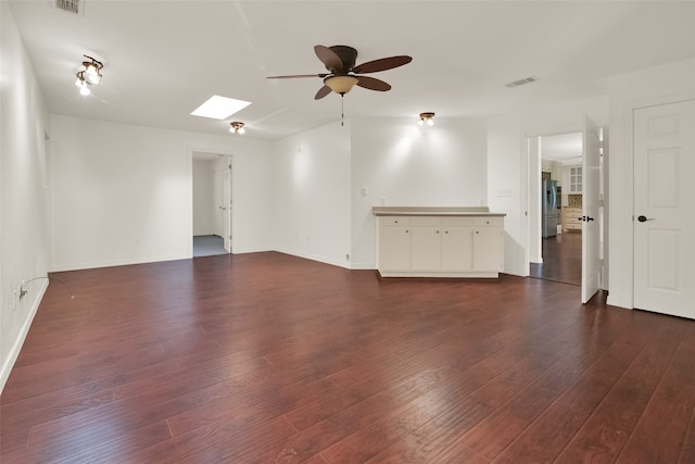 spare room featuring dark hardwood / wood-style floors, a skylight, and ceiling fan