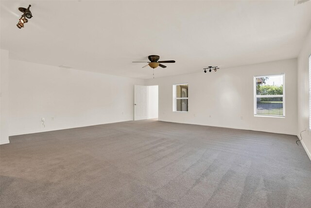 spare room featuring ceiling fan and dark carpet