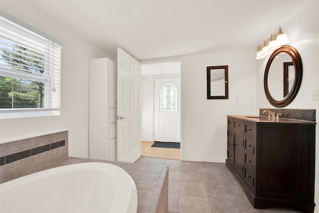 bathroom with tile patterned floors, vanity, a healthy amount of sunlight, and tiled bath