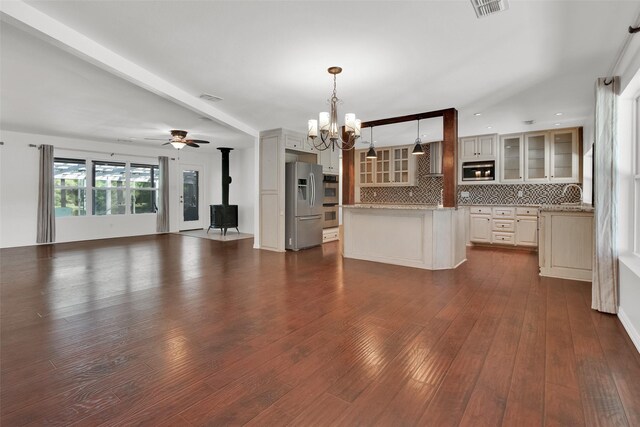 interior space featuring a wood stove, dark wood-type flooring, and ceiling fan with notable chandelier