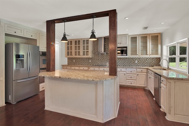 kitchen featuring pendant lighting, dark wood-type flooring, wall chimney range hood, sink, and appliances with stainless steel finishes