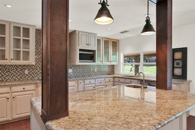 kitchen featuring pendant lighting, light stone counters, dark wood-type flooring, and cream cabinets