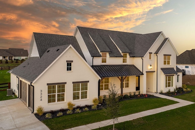 modern inspired farmhouse featuring a garage and a lawn