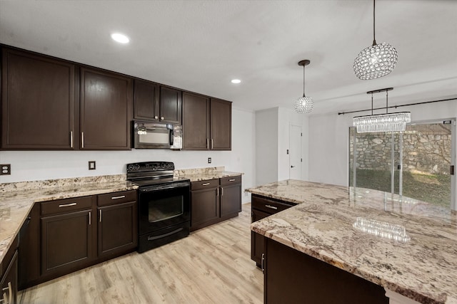 kitchen featuring pendant lighting, a kitchen island, black appliances, and light hardwood / wood-style flooring