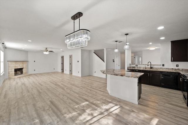 kitchen featuring dark brown cabinetry, ceiling fan, a stone fireplace, light hardwood / wood-style flooring, and decorative light fixtures