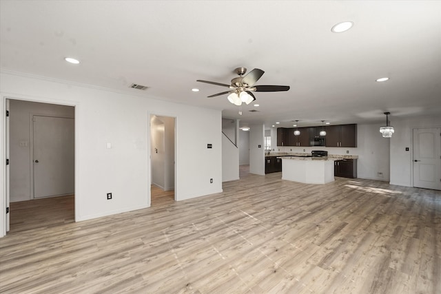 kitchen with a fireplace, black dishwasher, light hardwood / wood-style flooring, and hanging light fixtures