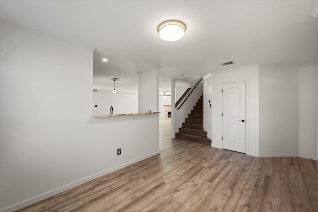 unfurnished living room featuring ceiling fan, light hardwood / wood-style flooring, and ornamental molding