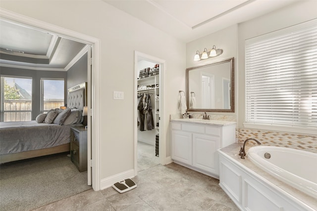 ensuite bathroom featuring a tray ceiling, a spacious closet, ensuite bathroom, vanity, and a bath