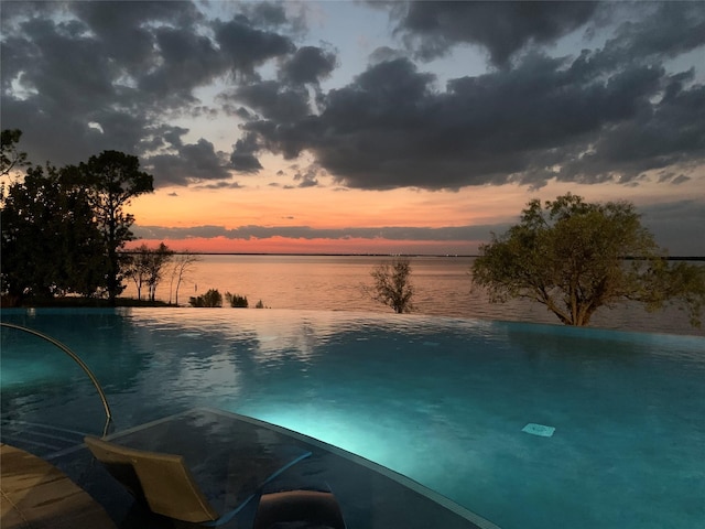 view of swimming pool with an infinity pool and a water view