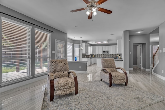 living room featuring ceiling fan with notable chandelier and light hardwood / wood-style floors