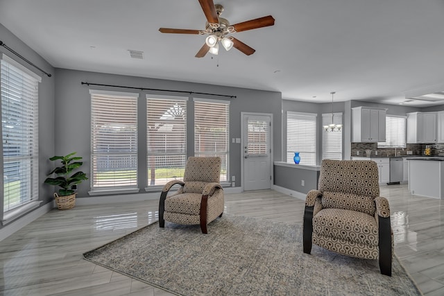 sitting room featuring plenty of natural light, ceiling fan with notable chandelier, and light hardwood / wood-style flooring