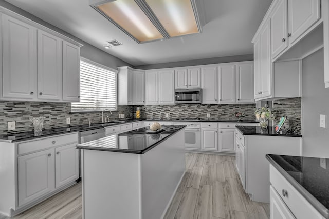 kitchen featuring backsplash, light hardwood / wood-style flooring, a kitchen island, white cabinetry, and stainless steel appliances