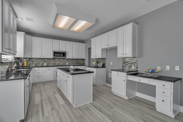 kitchen with white cabinets, tasteful backsplash, a kitchen island, and light hardwood / wood-style flooring