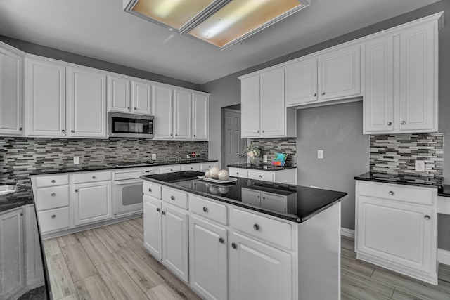 kitchen with decorative backsplash, a center island, light hardwood / wood-style flooring, and white cabinetry