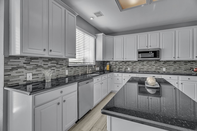 kitchen with backsplash, white cabinets, and stainless steel appliances