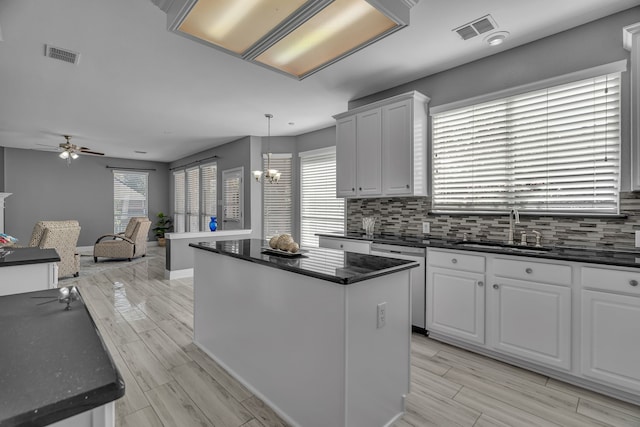 kitchen with decorative light fixtures, a center island, dishwasher, and white cabinetry