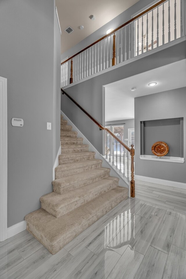 stairway featuring hardwood / wood-style floors and a towering ceiling