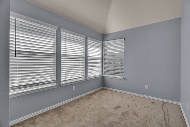 unfurnished room with light colored carpet and vaulted ceiling