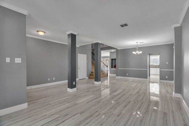 unfurnished living room featuring an inviting chandelier, ornate columns, ornamental molding, and light hardwood / wood-style flooring