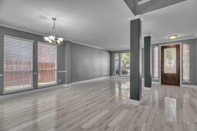 entryway featuring crown molding, an inviting chandelier, a healthy amount of sunlight, and light wood-type flooring