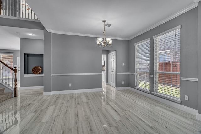 empty room featuring light hardwood / wood-style flooring, a notable chandelier, and ornamental molding