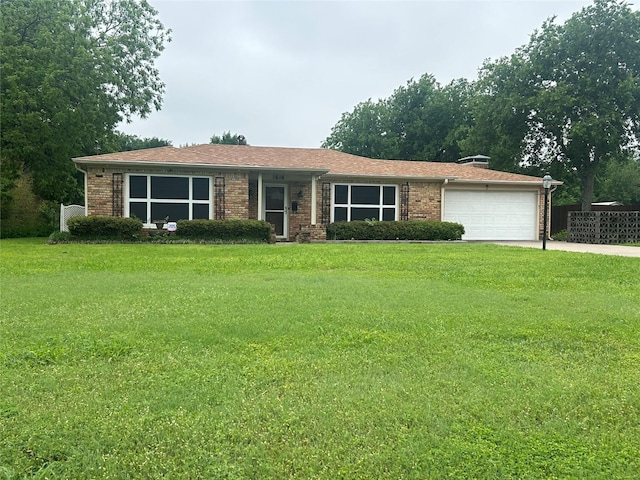 ranch-style home with brick siding, a garage, a front yard, and a shingled roof