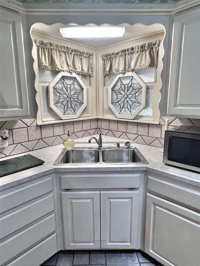 kitchen featuring tasteful backsplash, white cabinetry, and sink