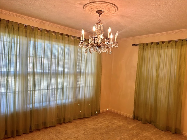 carpeted empty room featuring ornamental molding, a textured ceiling, and a chandelier